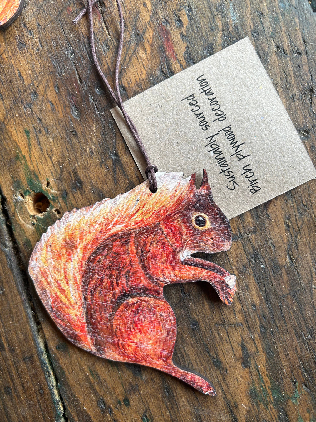 Wooden squirrel ornament with a kraft paper tag on a wooden surface