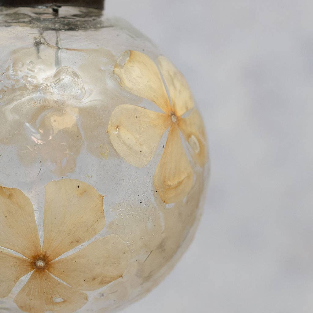Mouth-blown Christmas bauble with off-white flowers within the glass