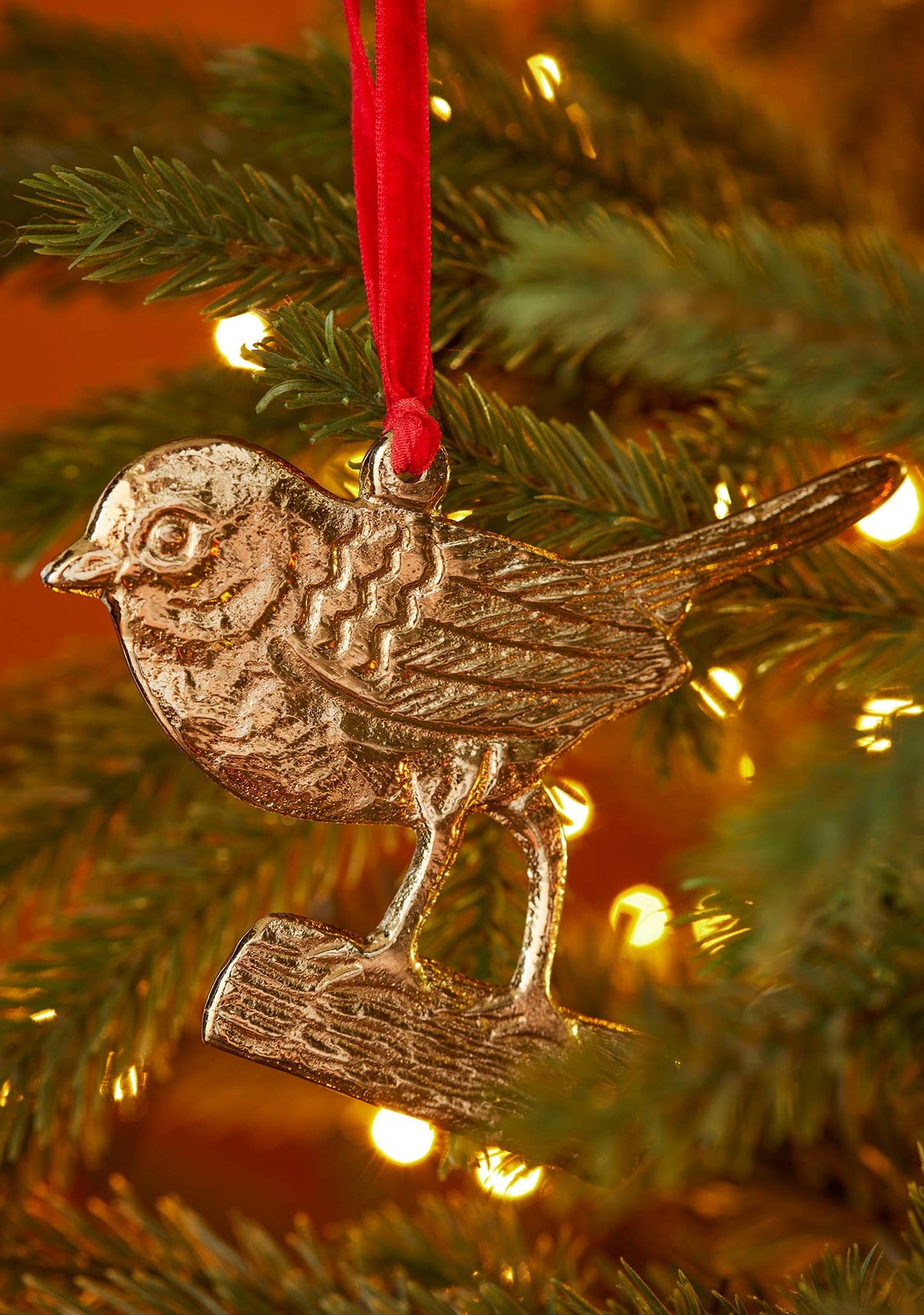 Robin on a branch Christmas decoration in gold-tone recycled aluminium on red velvet