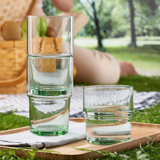 Stacked glass tumblers on a wooden tray with a picnic setting in the background