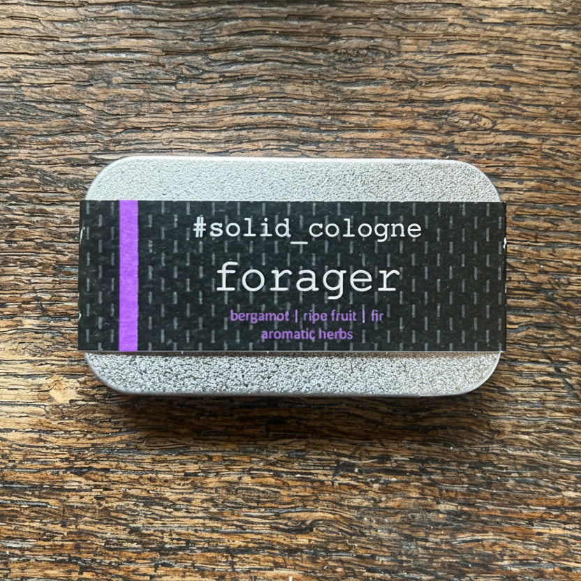 Solid cologne container with 'forager' label on a wooden surface