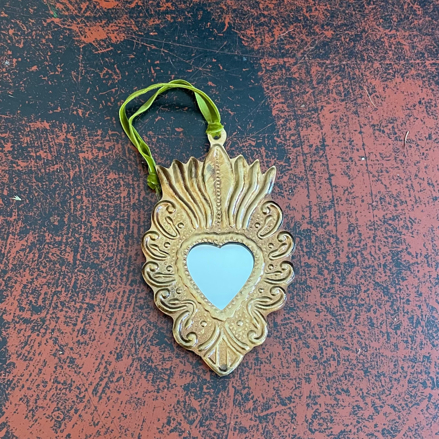 Decorative flaming heart-shaped mirror with a green velvet ribbon