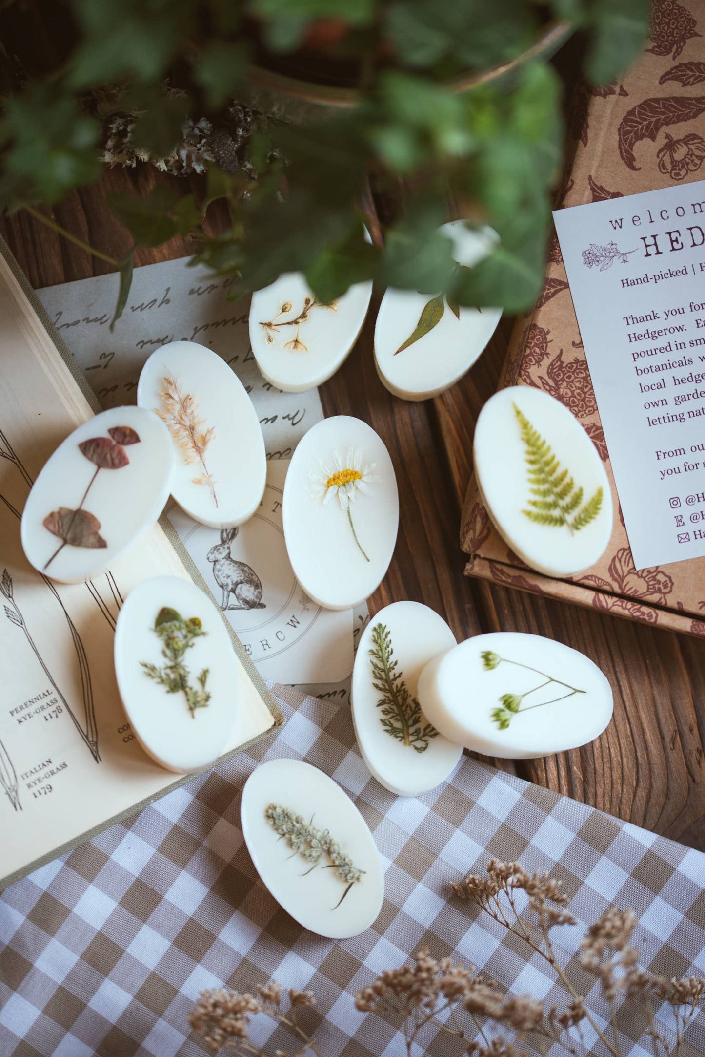 White oval wax melts with pressed flowers and leaves on a checkered surface
