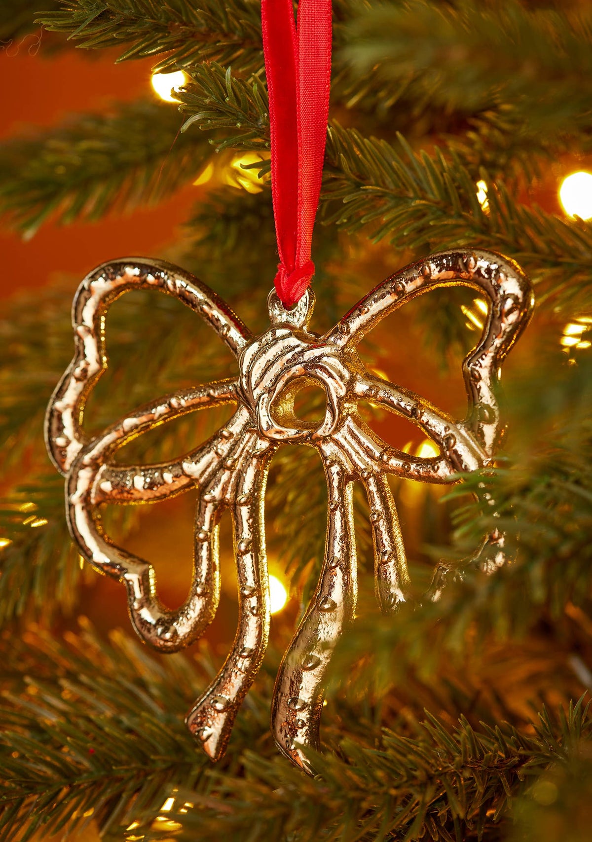 Ribbon bow Christmas decoration in gold-tone recycled aluminium on red velvet