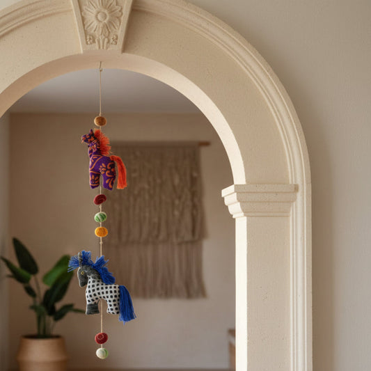 Decorative hanging mobile with colorful beads and animal figures on a white wall.