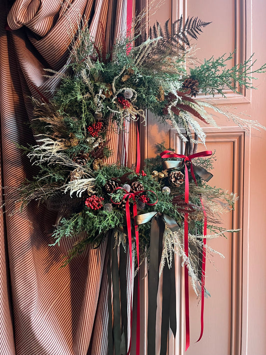 Christmas wreath workshop Glasgow, a wreath by Atelier Alicart with fern, conifer, pine cones and red and green ribbons at Kelvin Rooms