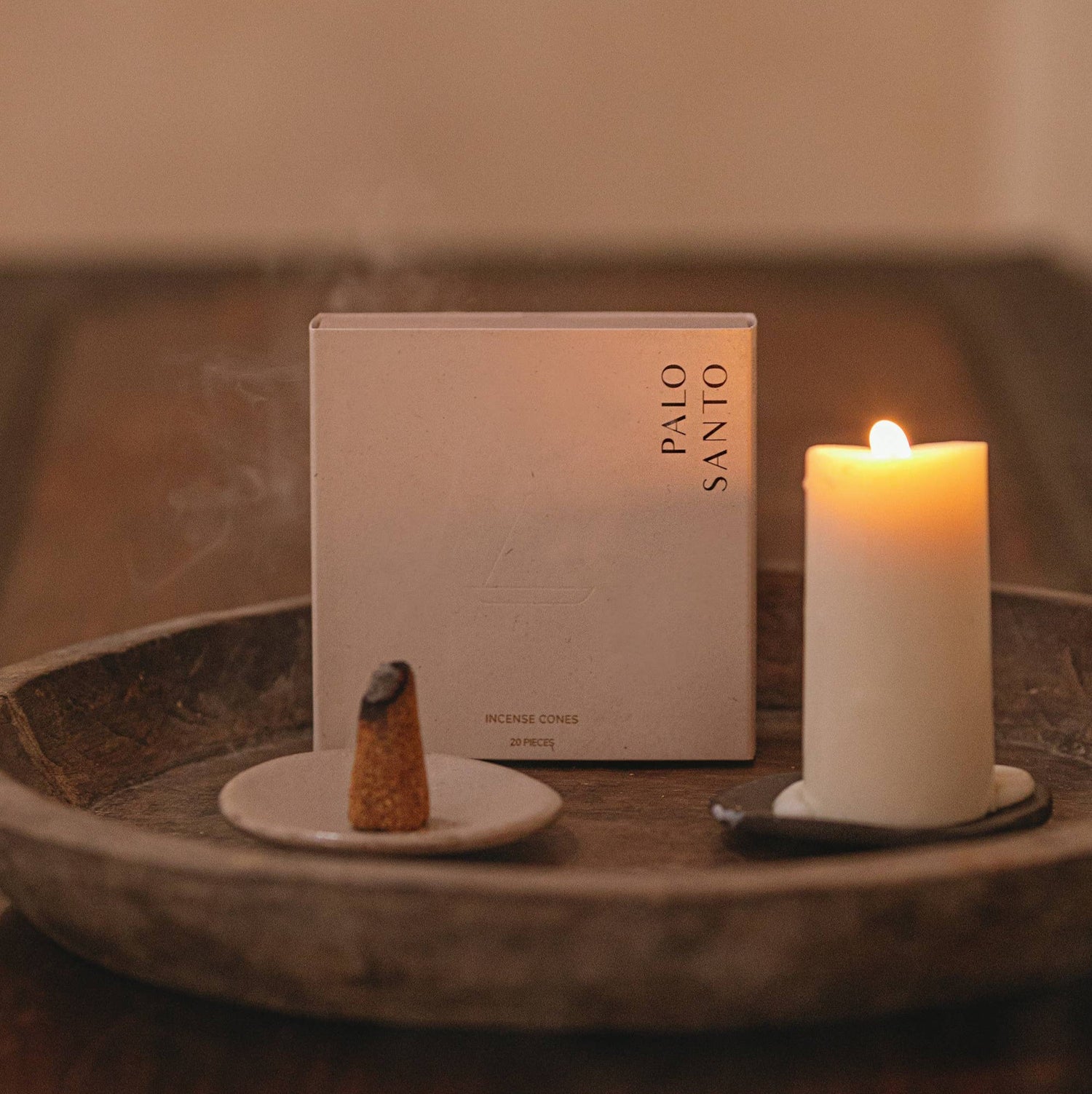 incense cones and a lit candle in a rustic bowl