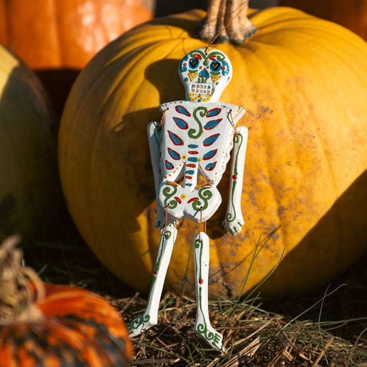 Hand-painted candy-skull patterns on a small hanging wooden skeleton