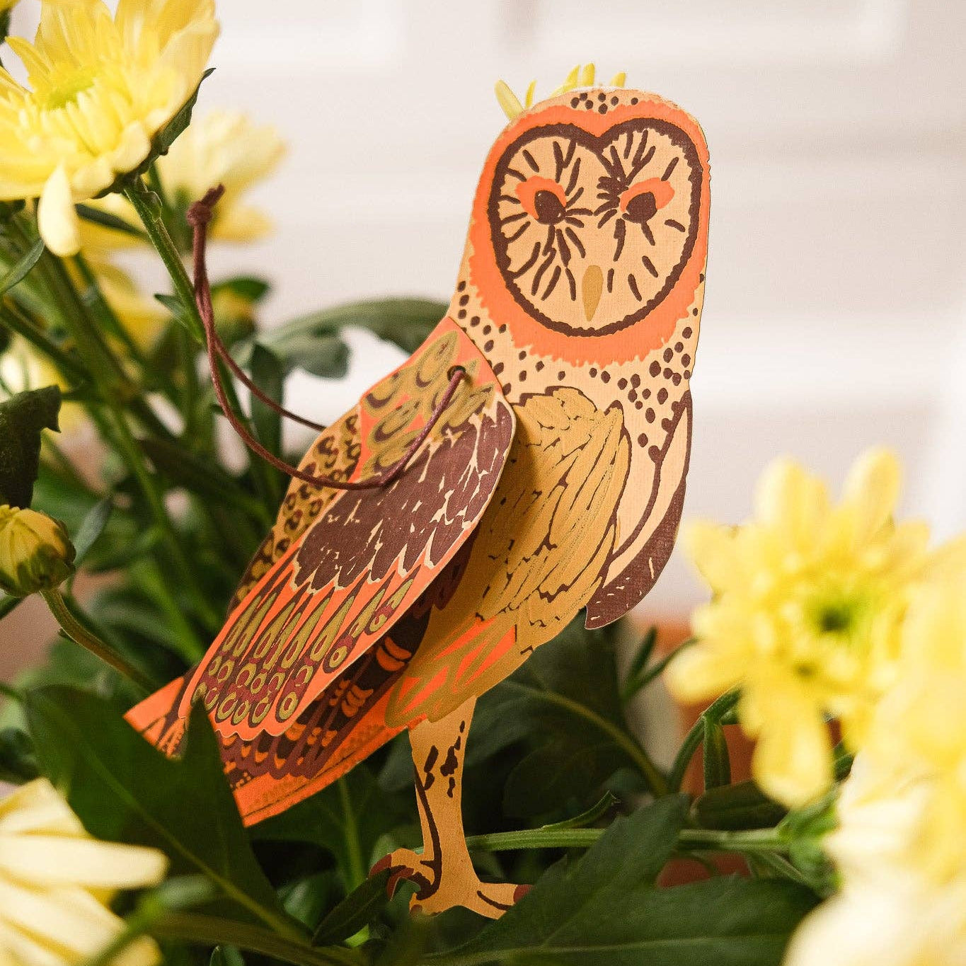 Decorative paper owl decoration among yellow flowers