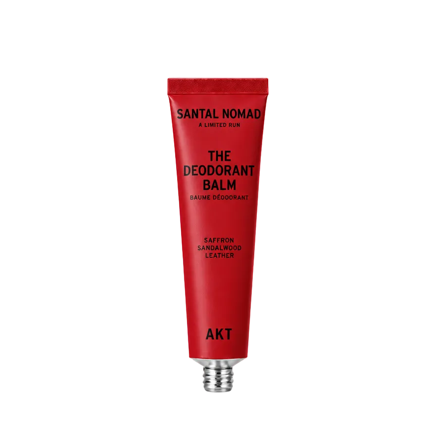 A red squeeze tube of Santal Nomad The Deodorant Balm by AKT, featuring black text and a silver metal cap, centered on a plain white background.