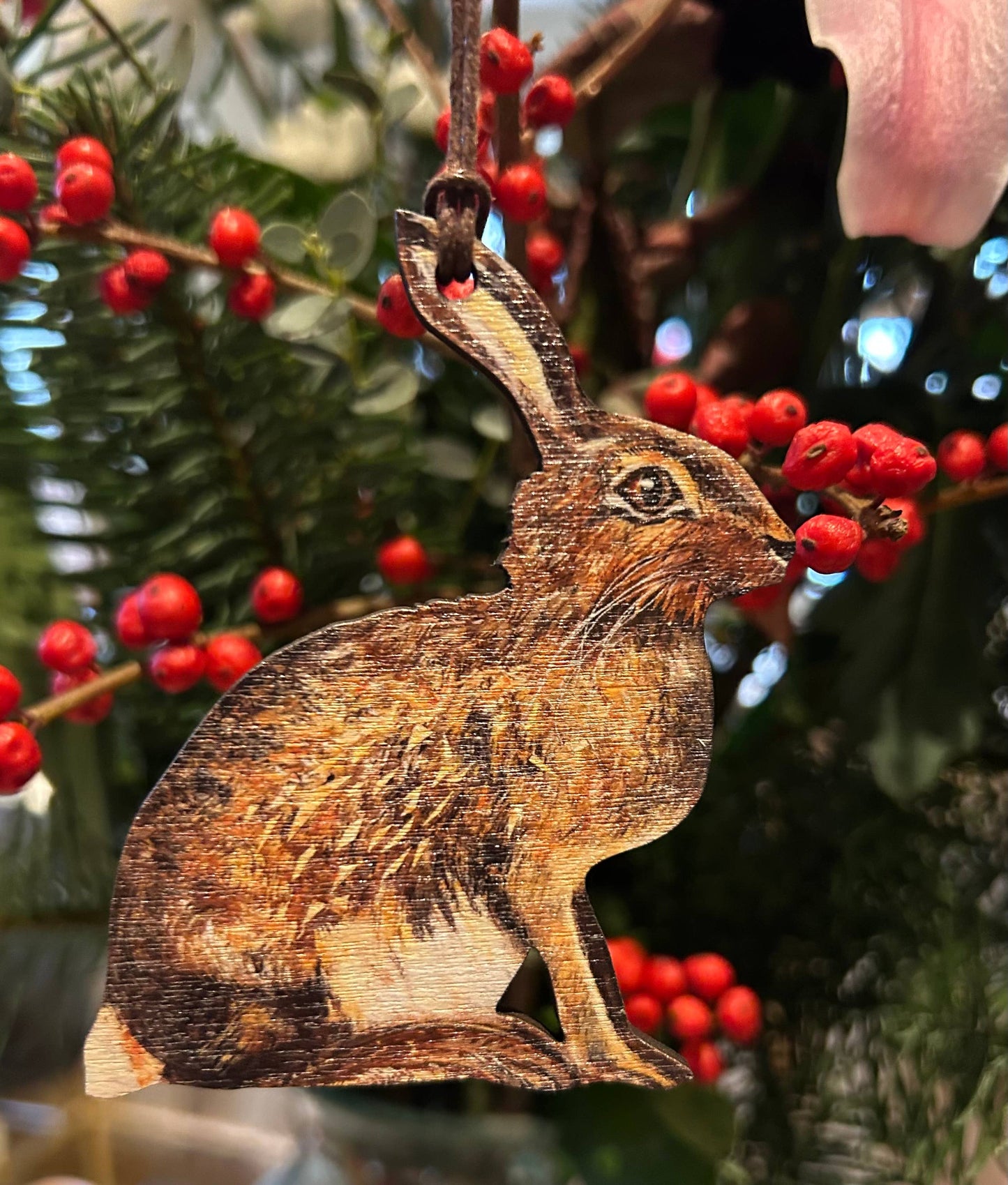 Wooden hare ornament with red berries on a green background