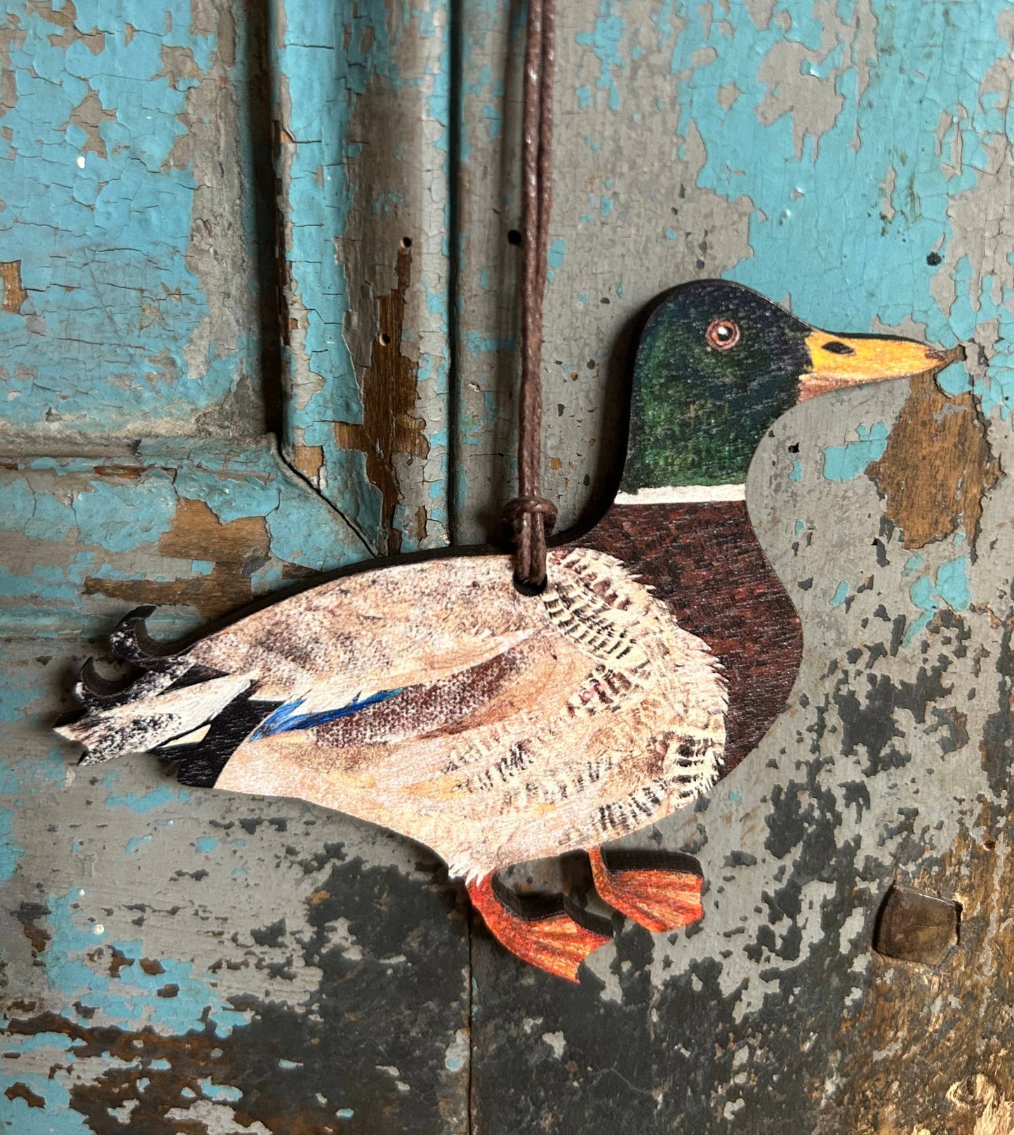 Decorative duck figure attached to a textured wooden surface with peeling paint.