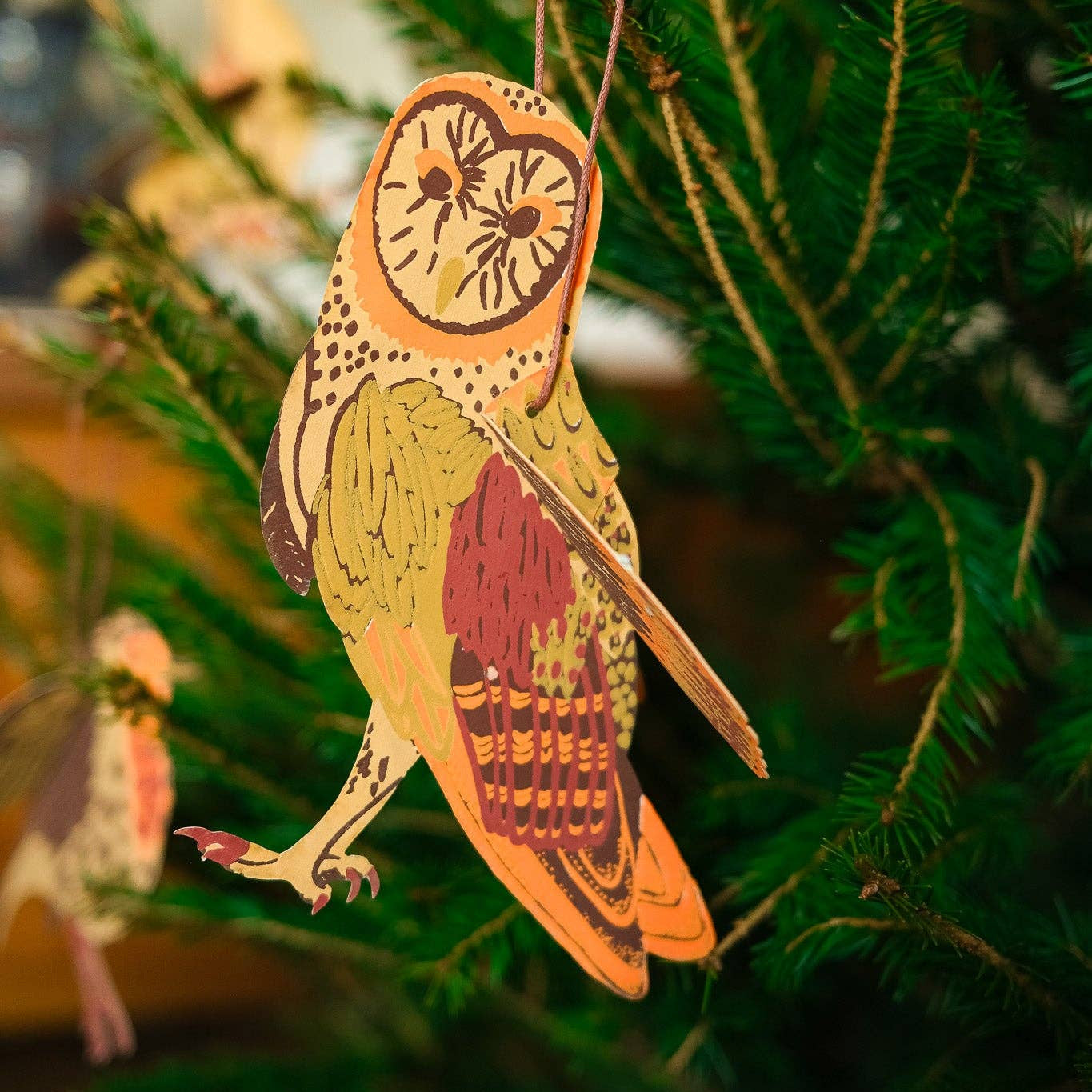 Decorative owl ornament hanging on a Christmas tree