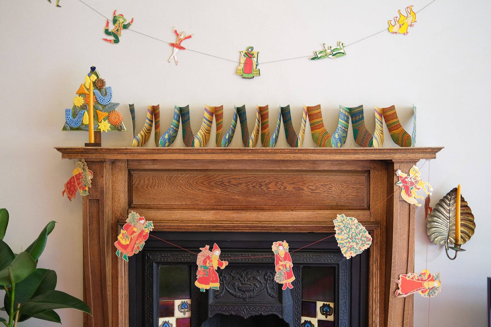 Decorative fireplace mantel with colorful sock garland and paper cutout decorations.