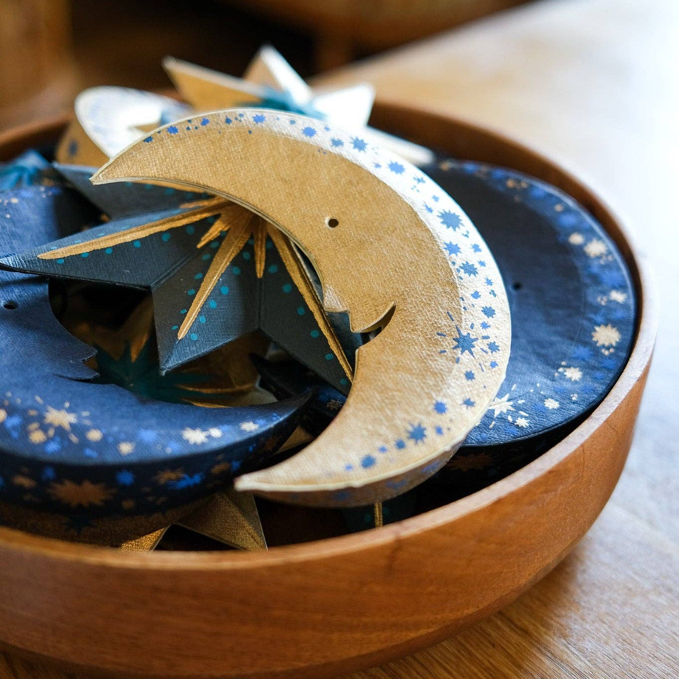 Wooden bowl with decorative items including a crescent moon design on a wooden surface.