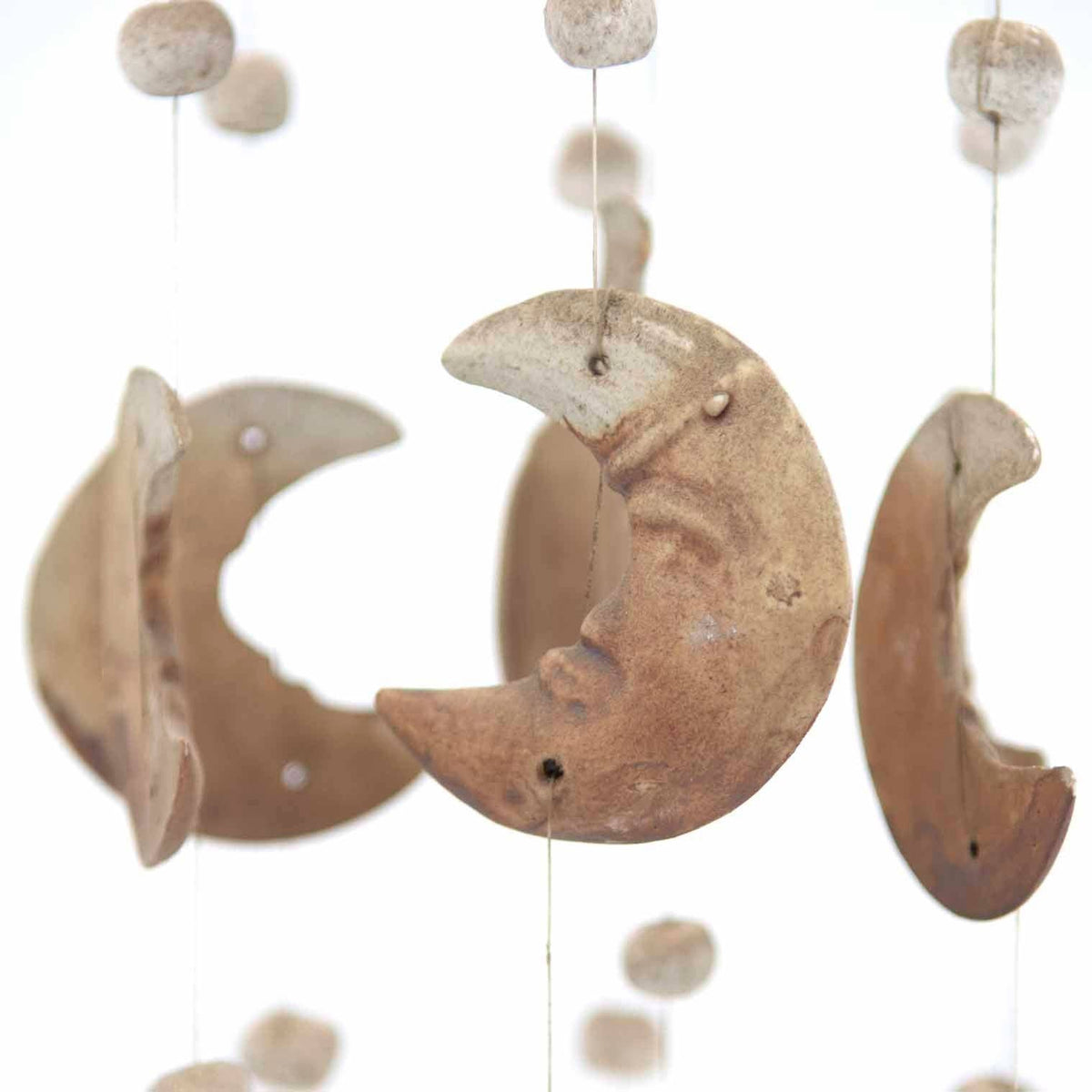 Detail of matt unglazed ceramic suns on a wind chime