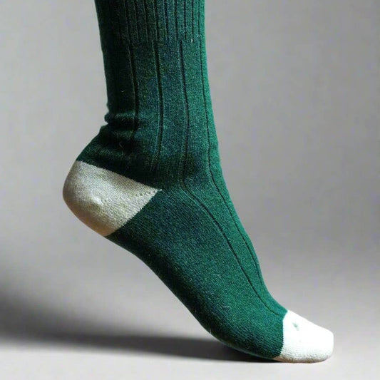 Green sock with white accents worn by a person on a gray background