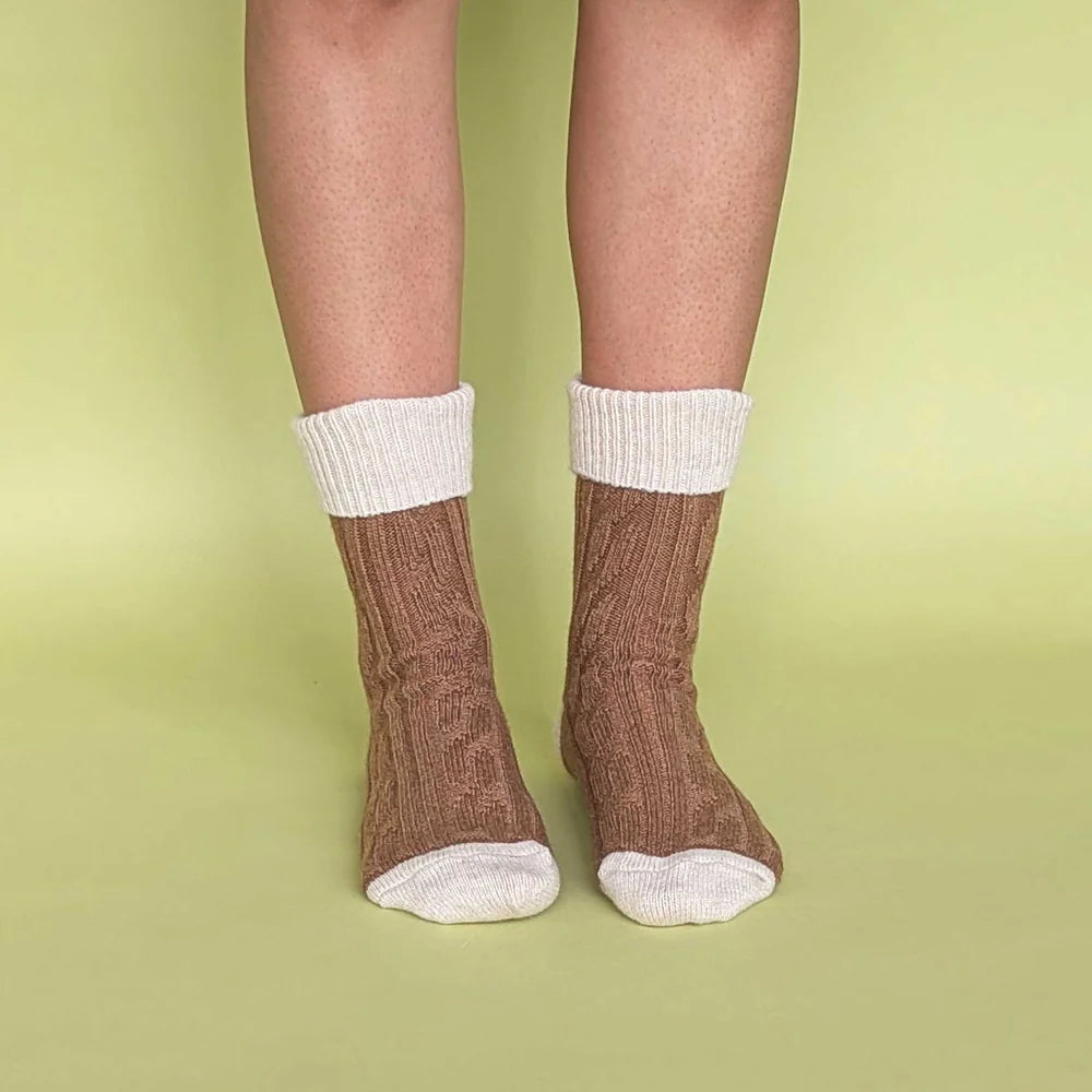 Brown wool socks with white accents worn by a person on a green background