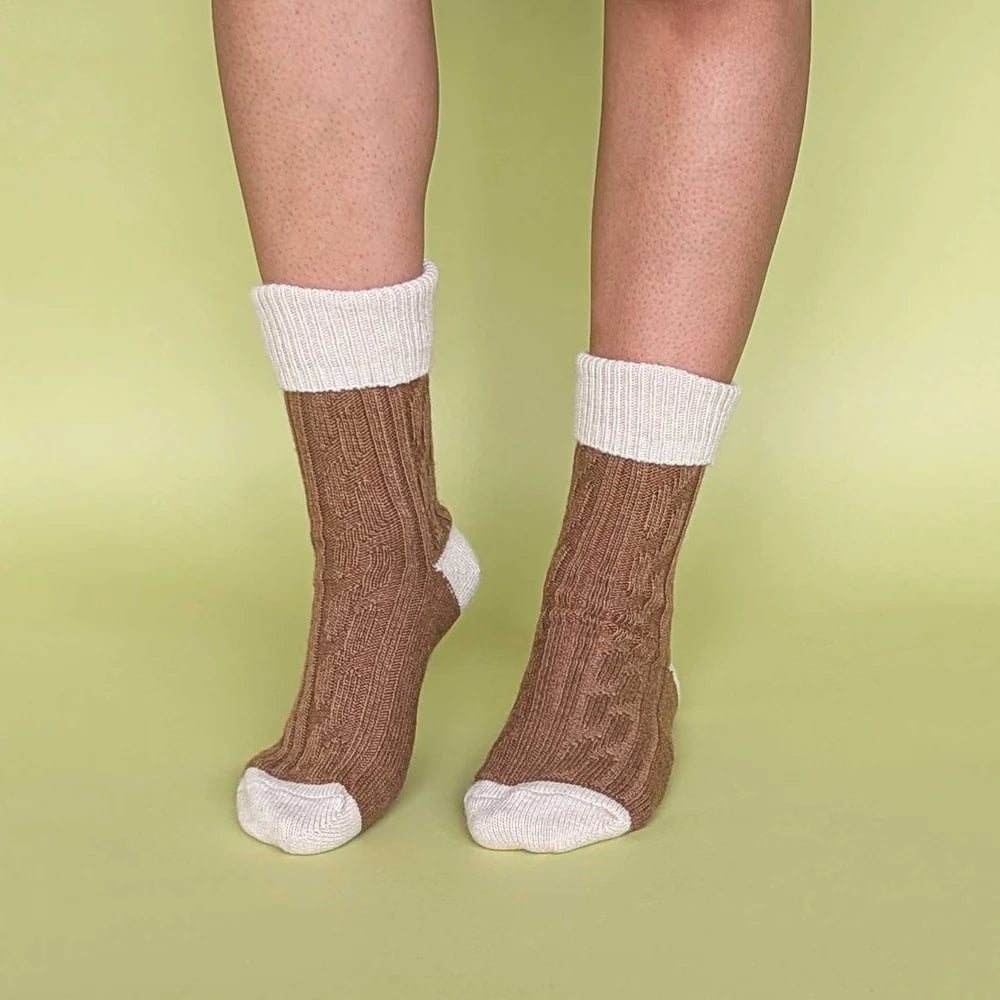 Brown socks with white cuffs and toes on a green background