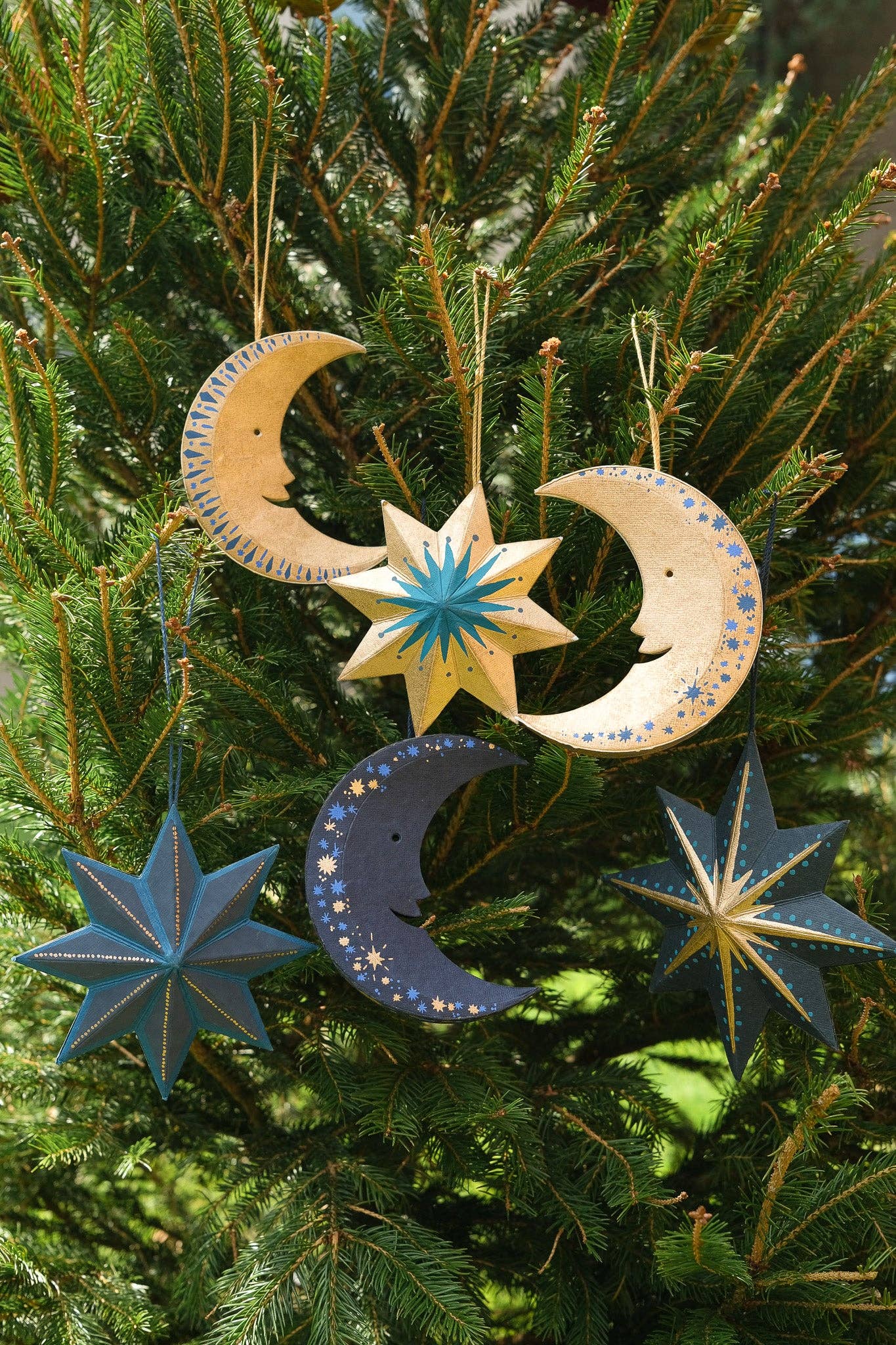 Decorative moon and star ornaments on a Christmas tree.