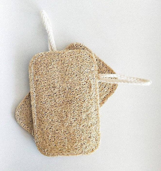 Flat lay of multiple loofah sponges arranged neatly on neutral background