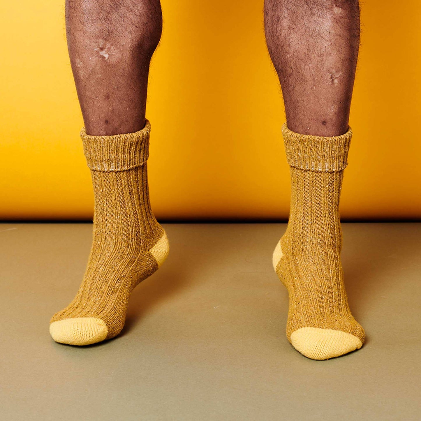 two tone yellow socks worn on feet against a yellow background