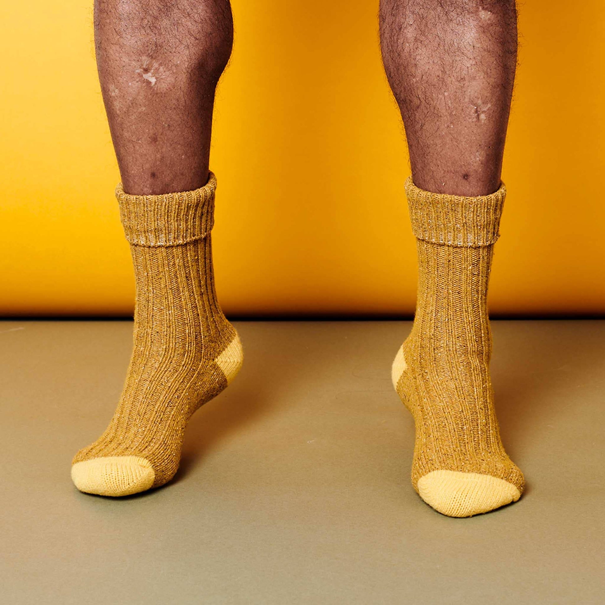 two tone yellow socks worn on feet against a yellow background