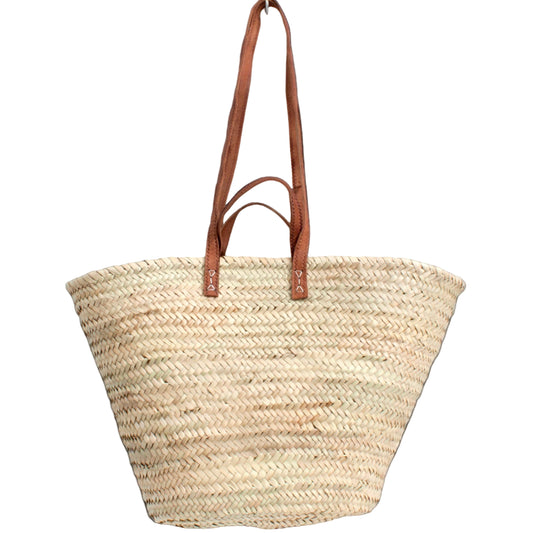 A market basket made of palm leaf with brown leather handles